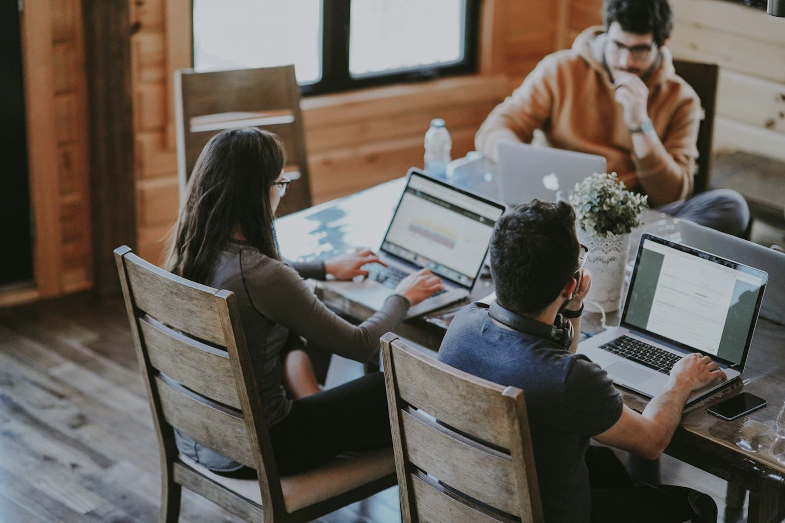 Een digitaal team werkt samen rond een tafel met laptops